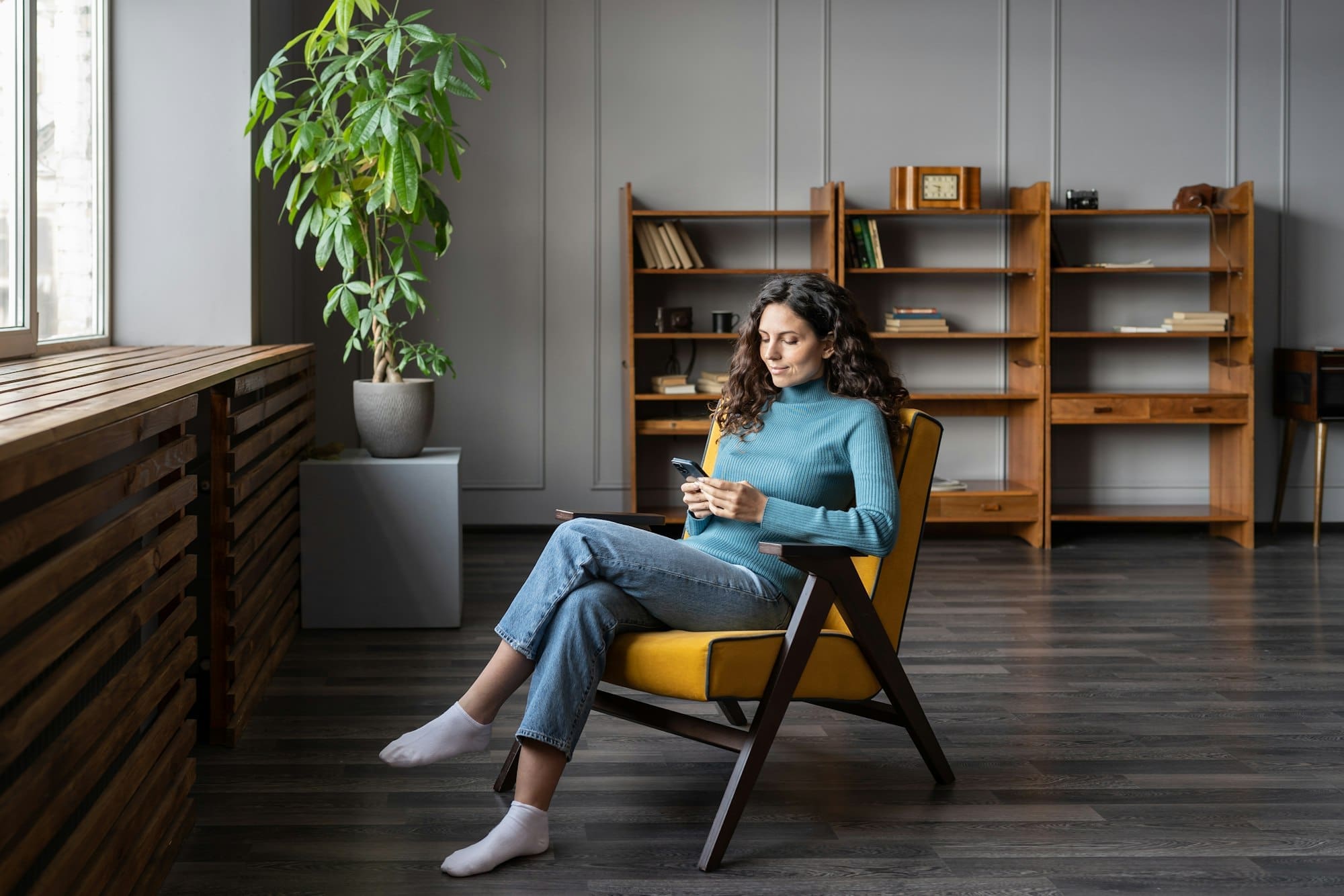 Young woman sit in cozy office space or at home sit in armchair browsing social media on smartphone